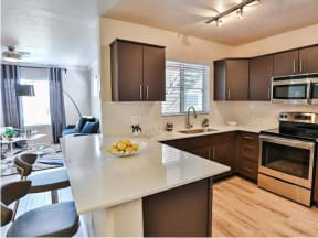 The Highland Apartments kitchen with brown cabinets, stainless appliances and quartz counters