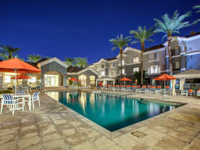 The Highland Apartments Pool as sunset with lounge seating, umbrellas, and palm trees