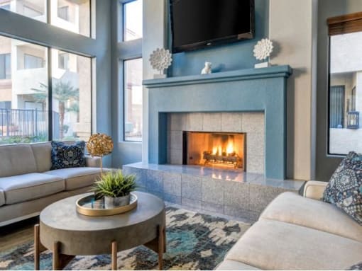 Ingleside Apartments Clubhouse Sitting area with blue fireplace with tv above and beige couches
