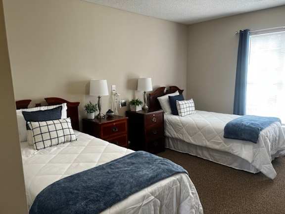 Two twin beds with blue blankets in a room with two nightstands.