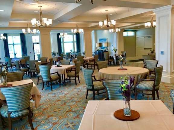 A dining room with tables and chairs and a carpet.