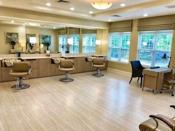 A spacious room with wooden floors and multiple chairs and tables.