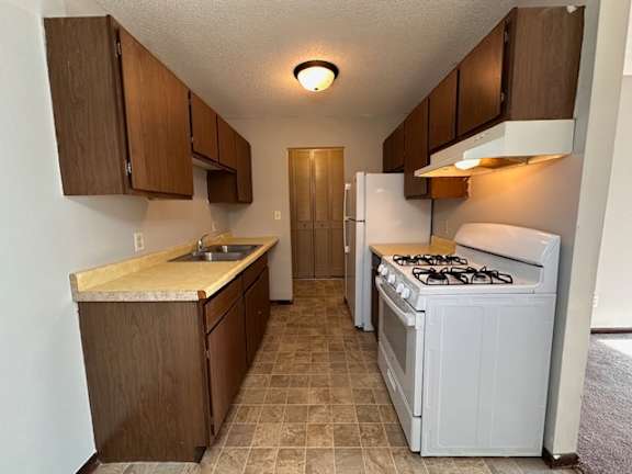 A kitchen with a white gas stove and brown cabinets.