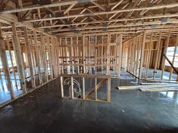 A room under construction with wooden beams and a concrete floor.