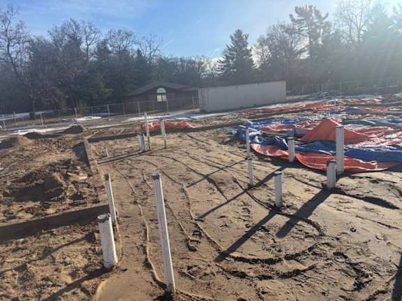 A construction site with a fence and a building in the background.