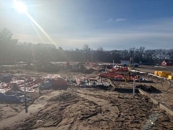 A construction site with a bright sun in the background.