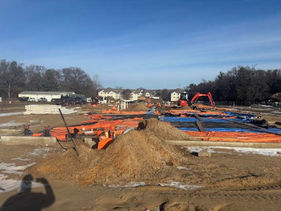 A construction site with a red excavator and orange safety barriers.