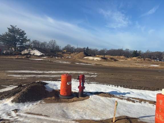 A construction site with orange barriers and a red fire hydrant.