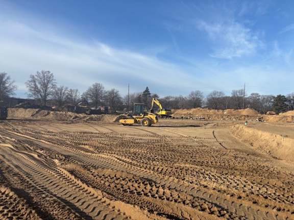 A yellow bulldozer is parked on a dirt field.