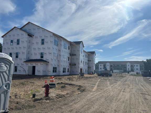 A construction site with a building under construction and a toilet in the foreground.