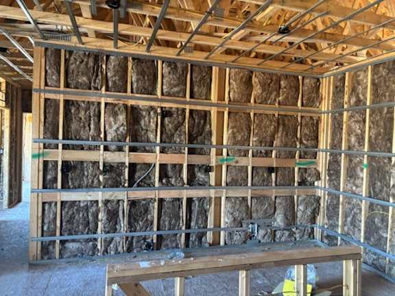 A room under construction with wooden beams and insulation.