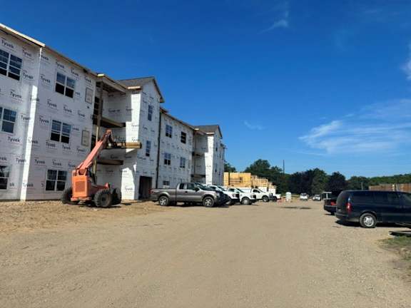 A construction site with a building under construction and vehicles parked nearby.