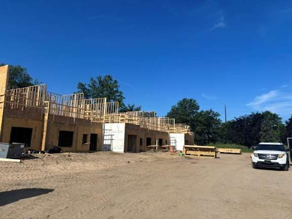 A construction site with a partially built building and a white van parked in front.