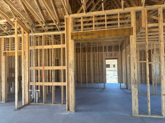 A view of a house under construction with wooden beams and no walls.