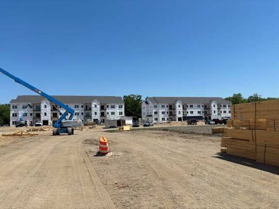 A construction site with a crane and apartment buildings in the background.