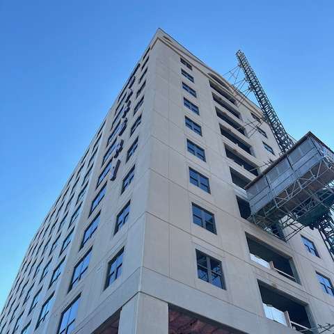 A tall building with a crane on the top and windows on the side.