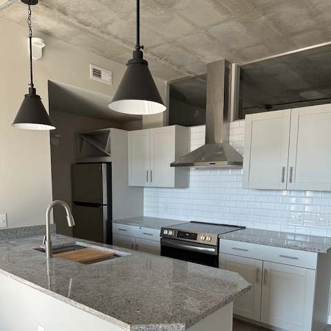 A modern kitchen with a large island and pendant lights.