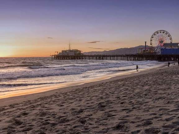 A beach scene with a pier and a Ferris wheel.