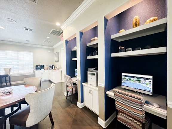 A room with a dining table and chairs, a computer on a desk, and a TV in the corner.