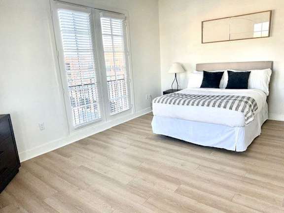 A bedroom with a large bed and a window with blinds.