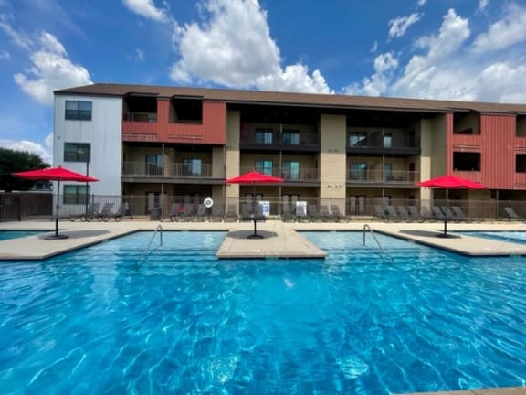 a swimming pool with umbrellas in front of a hotel at Aviator at Brooks, San Antonio, TX