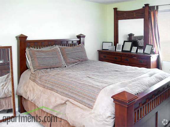 Large carpeted bedroom with four poster bedframe and mattress with grey bedding