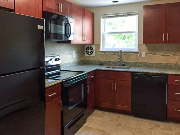 Kitchen with black appliances, granite counter tops, a tiled backsplash, and a window.