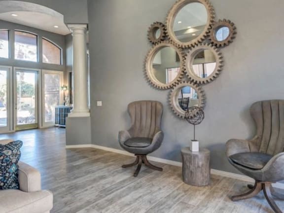 Ingleside Apartments Clubhouse sitting area with brown leather chairs, mirrors and light brown hardwood floors