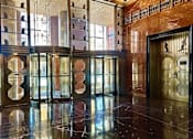 Thumbnail 23 of 23 - A hallway with marble floors and a series of doors with windows.