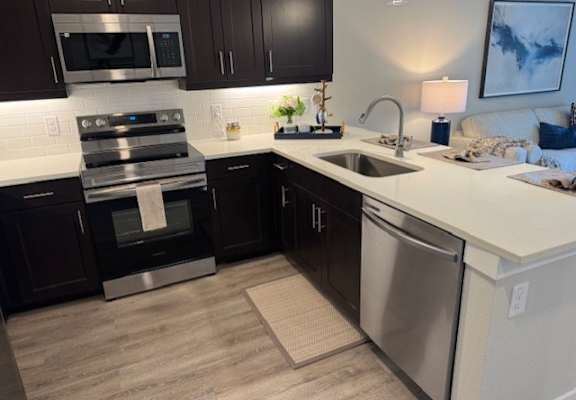 A modern kitchen with dark brown cabinets and stainless steel appliances.