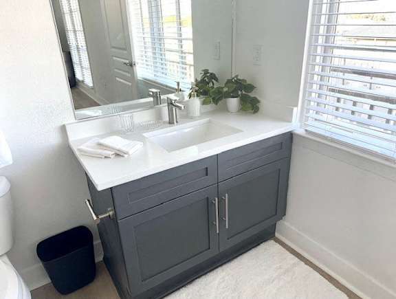 A bathroom with a white countertop and a grey cabinet.