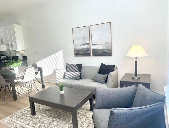 A living room with a grey couch, a coffee table, and a lamp.