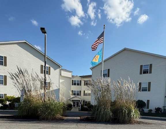 A white building with a flag on top and a blue flag on the right side.