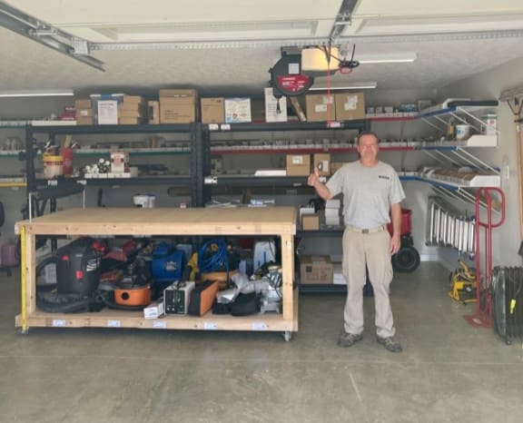 a man standing next to a wooden shelf in a garage