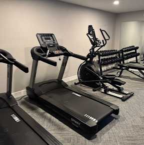 A gym with treadmills, elliptical machines, and other exercise equipment.