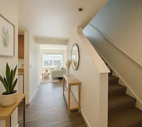 A hallway with a staircase and a table with a plant on it.