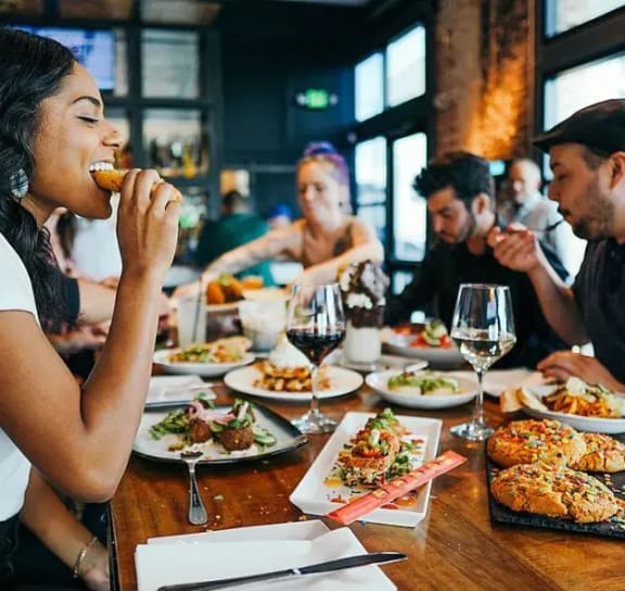 a group of people sitting around a table eating food
