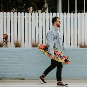 A man is walking with a skateboard in his hand.
