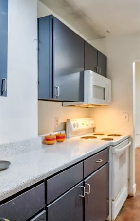 A kitchen with a white microwave above a stove and a white dishwasher.