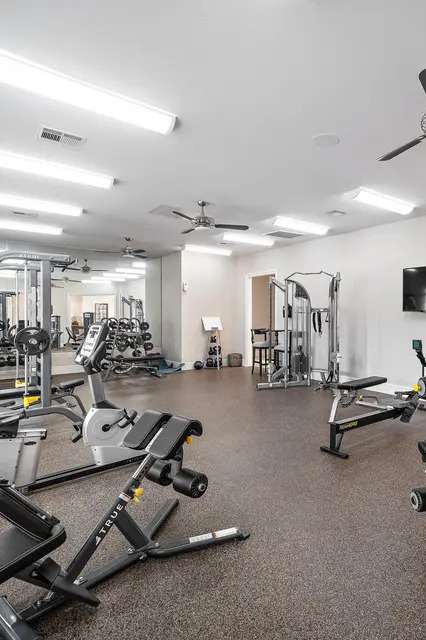 A spacious gym with a variety of equipment including treadmills, weight machines, and a television.