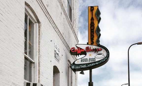 A white building with a sign that says "Coffee Shops Good Food".