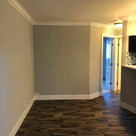 A room with a wooden floor and a doorway leading to another room.