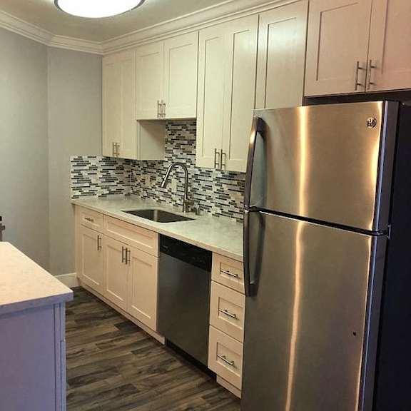 A kitchen with a stainless steel refrigerator and white cabinets.