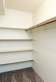 A white shelving unit with a brown carpet on the floor.