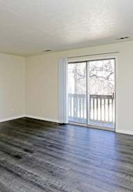 A room with a sliding glass door and wooden flooring.