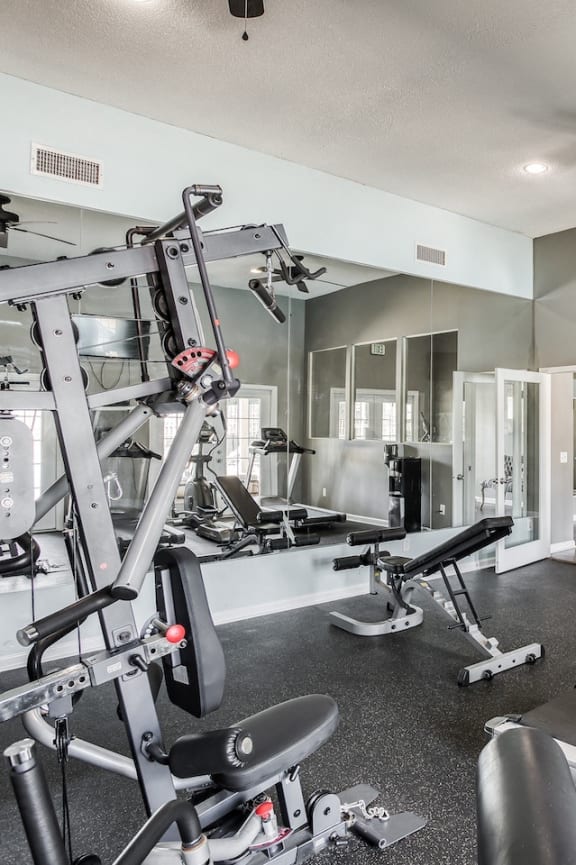 a fitness center with a wall sized mirror and strength and cardio equipment