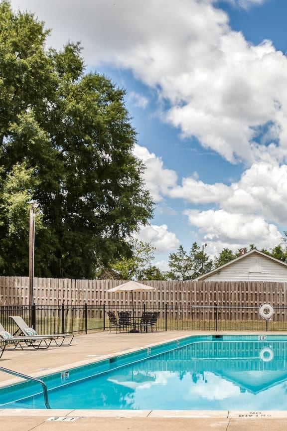 a large swimming pool and sundeck with lounge chairs and tables with chairs and umbrellas