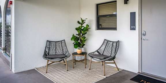 two hammocks on a porch overlooking a pool with palm trees