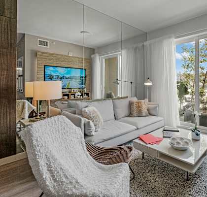 A modern living room with a grey sofa, a white chair, and a television.