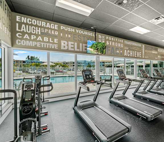 A gym with treadmills and a wall of motivational words.